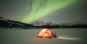 Photographer in a tent lit up by Northern Lights (aurora borealis) and starry sky in the polar night, Svensby, Lyngen Alps, Troms, Norway, Scandinavia, Europe ©Roberto Moiola/robertharding.com