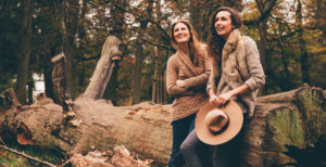 Two female friends leaning on tree trunk in an autumnal park ©Alamy Stock Photo