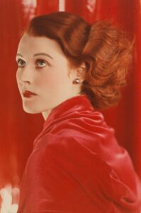 Portrait of Joan Maude by Yevonde, a white woman with auburn hair and red shawl