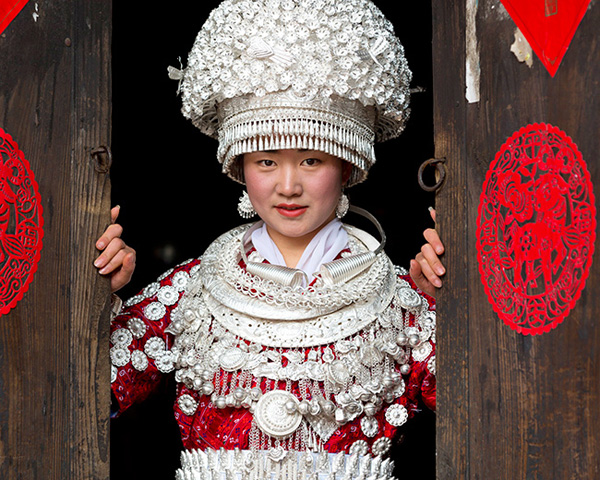 China, Guizhou, Miao woman dressed in traditional costume, wearing a hat that weighs 5 kgs ©Tim Mannakee/4Corners Images