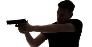 A Figurestock image of a man, in silhouette, pointing a gun – shot from eye level.
