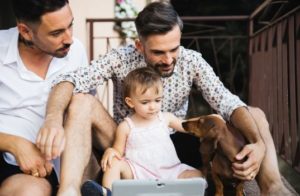 Male gay couple with young child and dog