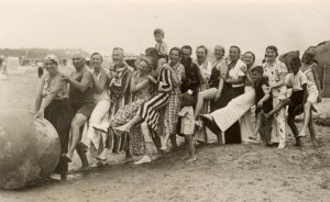 A wonderful photograph of a very jolly group (possibly one large extended family) playing with a huge ball on the beach - note the variety of magnificent beachwear on show!! Encapsulating the joy of the British seaside holiday in one image... circa 1930
