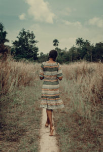 Nigeria, Delta state, Rear view of woman in patterned dress walking in field